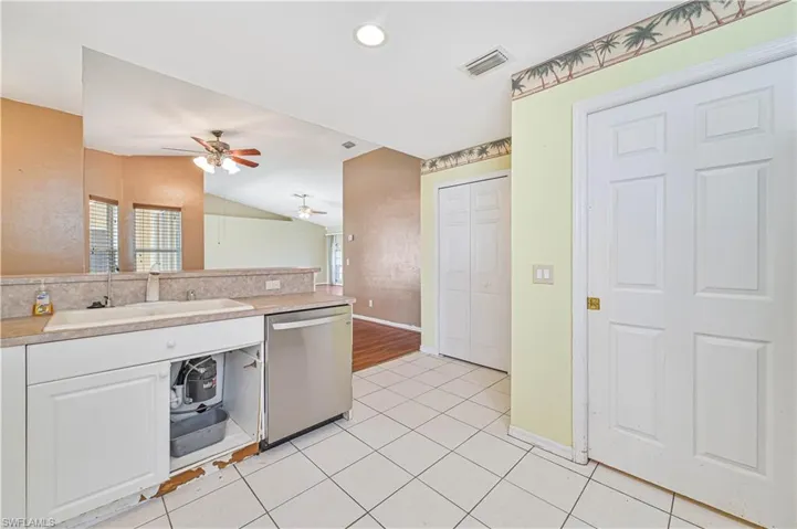 Kitchen featuring ceiling fan, stainless steel dishwasher, white cabinetry, light tile patterned floors, and sink