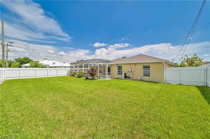 Back of property featuring glass enclosure and a yard