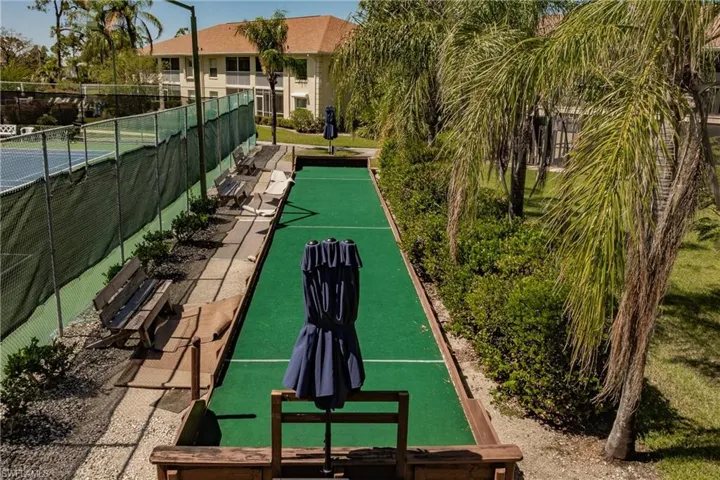 View of property's community with a tennis court and fence