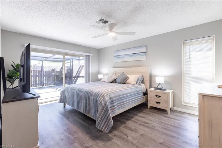 Large primary bedroom with abundant lighting and open to laniabaseboards, wood finished floors, a ceiling fan, and access to outside