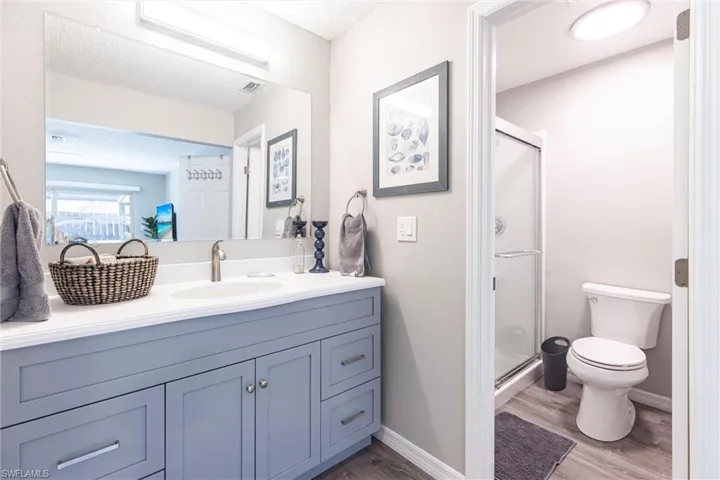Full bathroom featuring a shower stall, vanity and matching flooring throughout.
