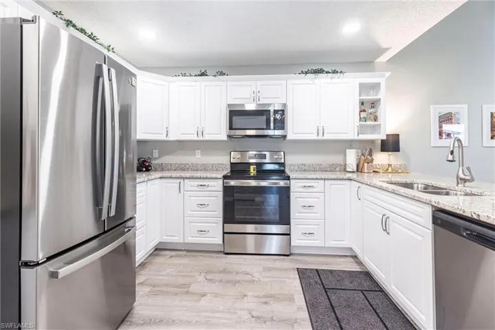 Kitchen features all new SS appliances light wood-style floors, white cabinetry, and stainless steel appliances