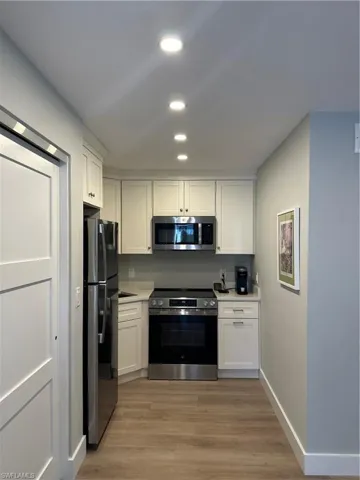 Kitchen with light countertops, white cabinetry, fridge, range, and stainless steel microwave