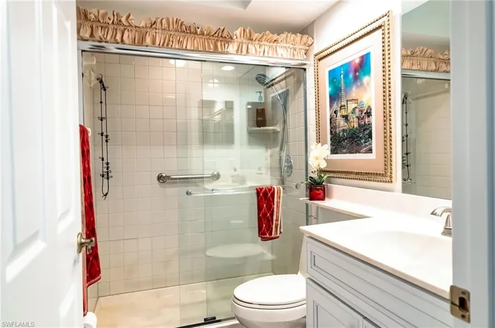 Bathroom featuring vanity, toilet, and a shower with door