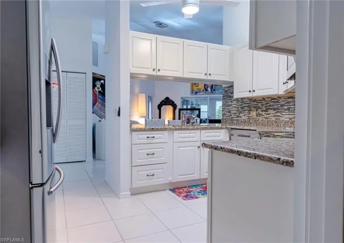 Kitchen featuring white cabinets, light tile patterned flooring, kitchen peninsula, and stainless steel refrigerator