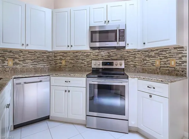 Kitchen featuring tasteful backsplash, white cabinets, and appliances with stainless steel finishes