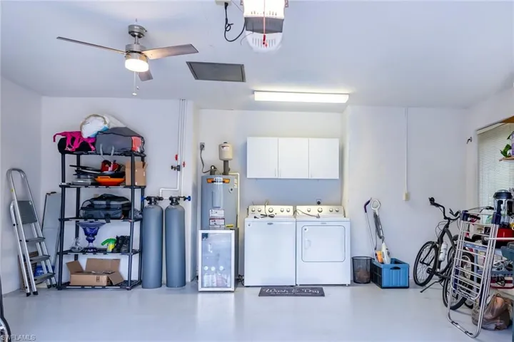 Garage with separate washer and dryer, water treatment equipment, ceiling fan, water heater, and a garage door opener