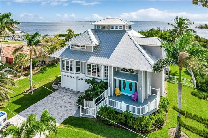 Aerial view of property featuring a water view, a yard, decorative driveway, and a garage