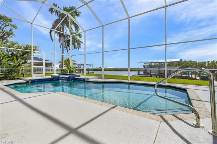 View of swimming pool with a water view, a pool with connected hot tub, glass enclosure, a sunroom, and a patio area