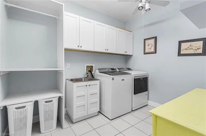 Laundry area with light tile patterned floors, separate washer and dryer, a ceiling fan, and cabinet space