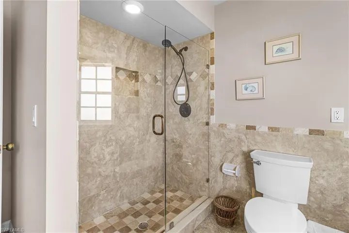 Bathroom featuring a stall shower and tile walls