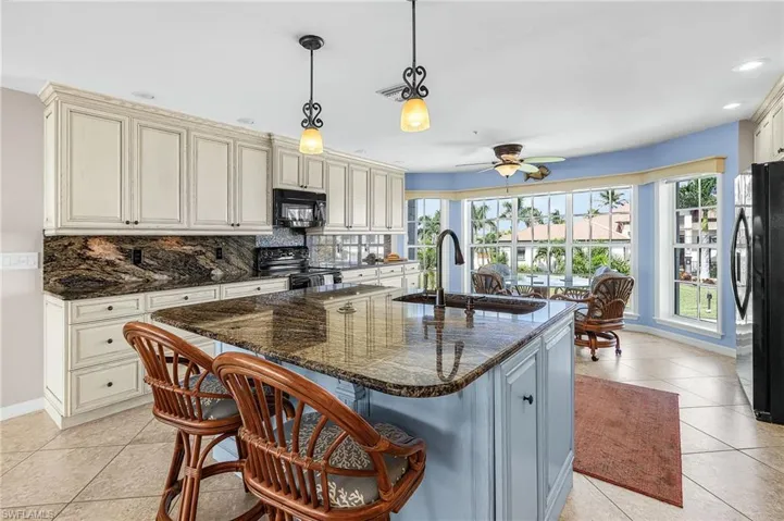 Kitchen with cream cabinets, light tile patterned flooring, backsplash, and recessed lighting