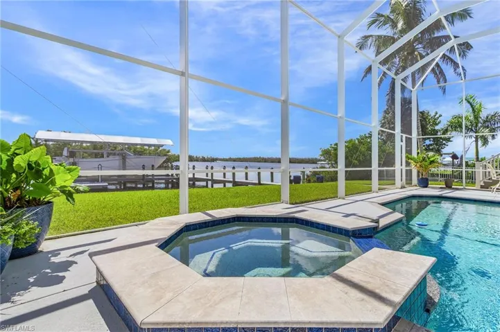 View of swimming pool featuring a water view, a lawn, a lanai, and a pool with connected hot tub