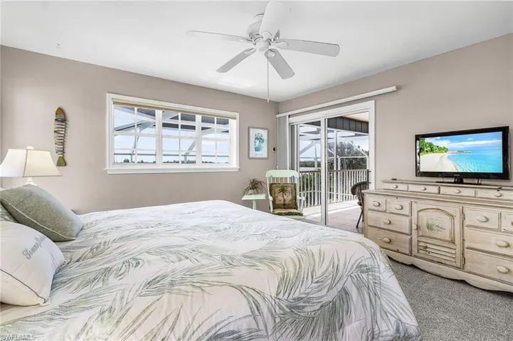 Bedroom with light colored carpet, multiple windows, ceiling fan, and access to outside