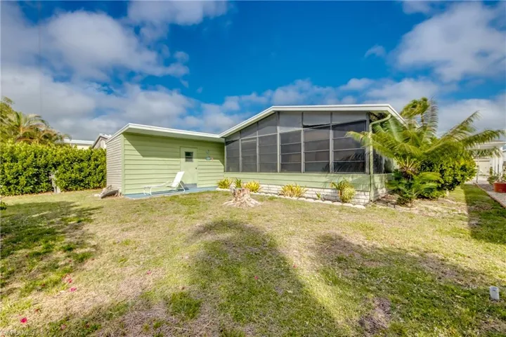 Rear view of house with a sunroom and a yard