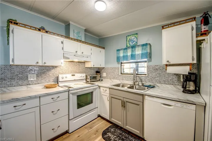 Kitchen with white appliances, light wood finished floors, decorative backsplash, a textured ceiling, and white cabinets