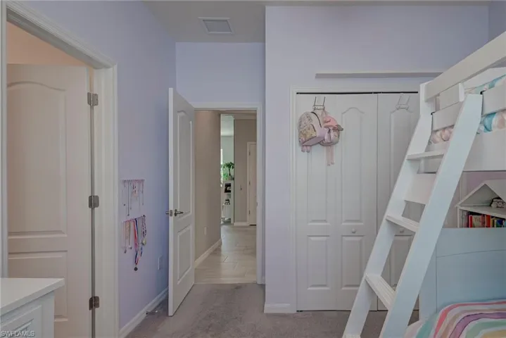 Bedroom with light carpet and a closet