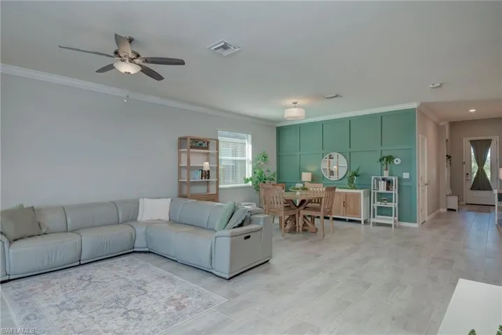 Living area featuring ornamental molding, decoratve feature wall and ceiling fan