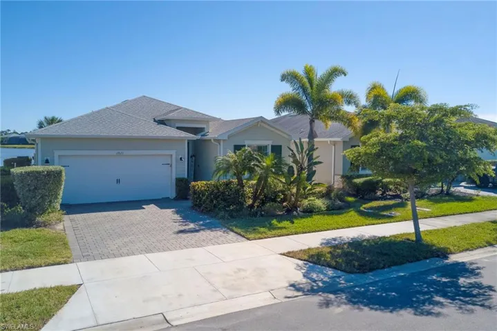 Ranch-style house featuring driveway, an attached garage, and a front lawn