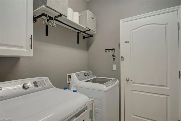 Washroom featuring a textured wall, washing machine and dryer, and cabinet space