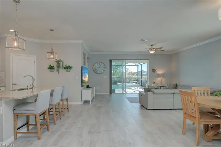 Dining space featuring crown molding, ceiling fan, and light wide plank tile flooring