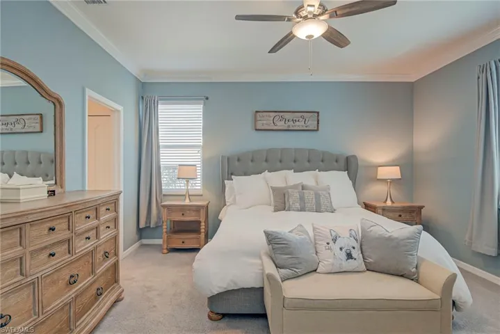 Owners Bedroom with light carpet, crown molding, custom paint and ceiling fan