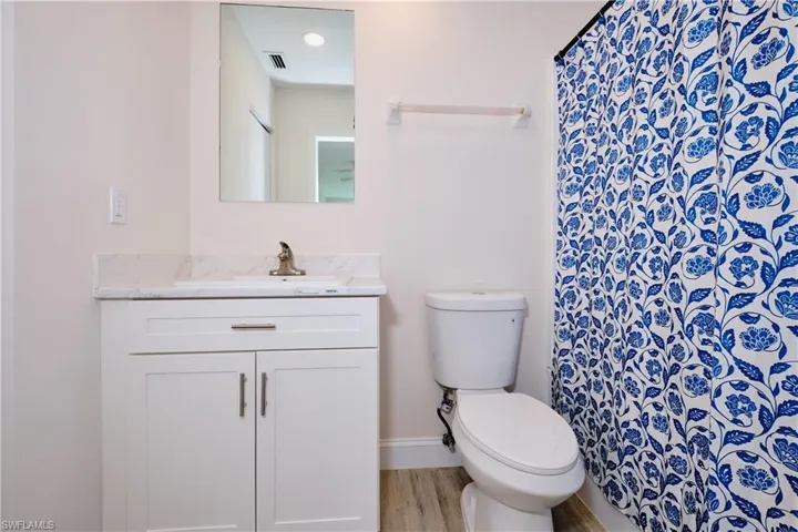 Bathroom with curtained shower, vanity, and light wood-type flooring