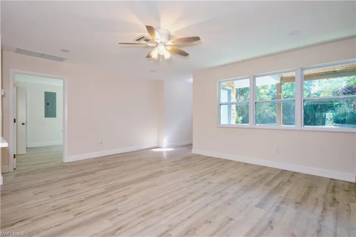 Empty room featuring light wood finished floors, electric panel, and ceiling fan