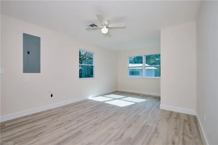 Empty room featuring electric panel, light wood-style floors, healthy amount of natural light, and ceiling fan