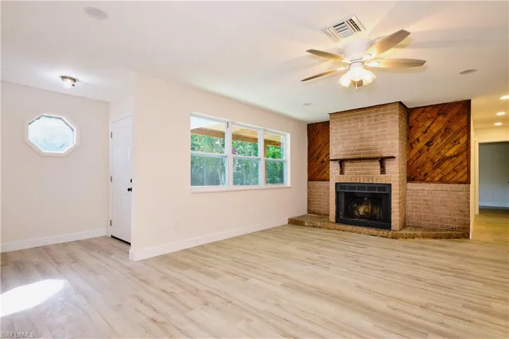 Unfurnished living room featuring light wood-style floors, ceiling fan, a brick fireplace, and recessed lighting