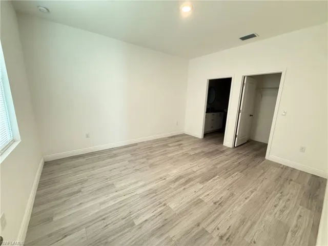 Unfurnished bedroom featuring a walk in closet, light wood-style floors, and connected bathroom