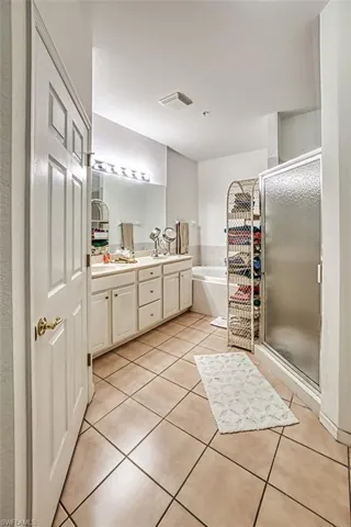 Bathroom featuring dual vanity, tile patterned floors, and separate shower and tub