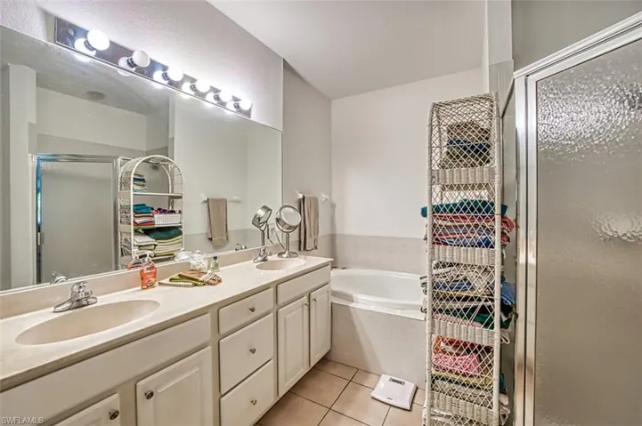 Bathroom featuring double vanity, plus walk in shower, and tile patterned floors