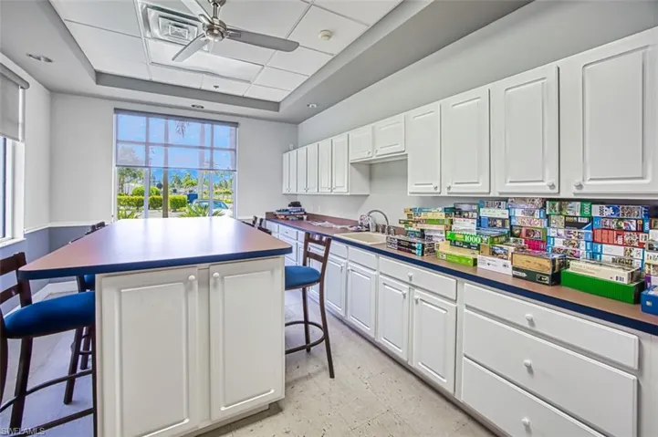 Kitchen featuring ceiling fan, light tile patterned flooring, a raised ceiling, and a center island