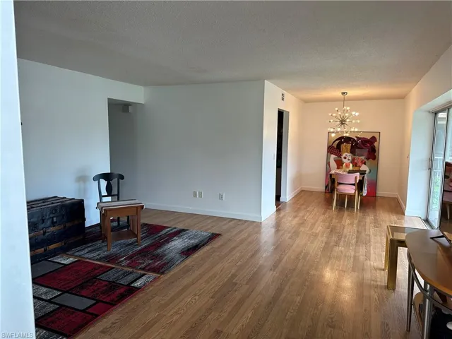 Sitting room with wood-type flooring, a textured ceiling, and a chandelier
