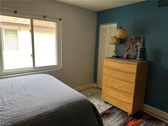 Bedroom with multiple windows, a textured ceiling, light carpet, and a closet