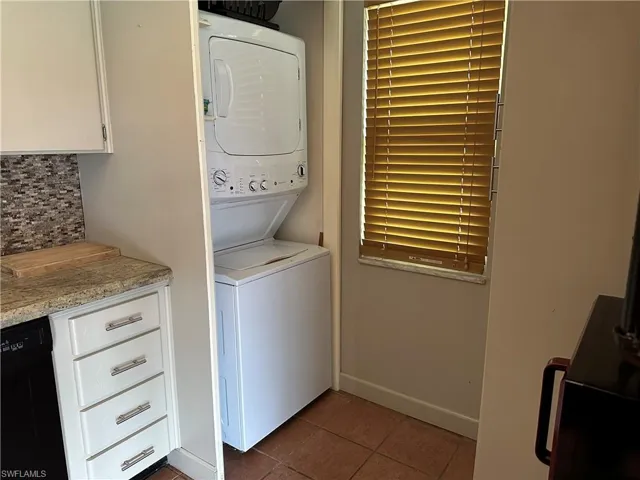 Washroom featuring tile patterned floors and stacked washing maching and dryer