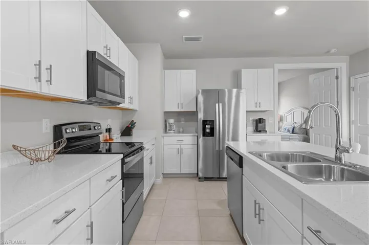 Kitchen featuring stainless steel appliances, white cabinetry, recessed lighting, light tile patterned floors, and light stone countertops