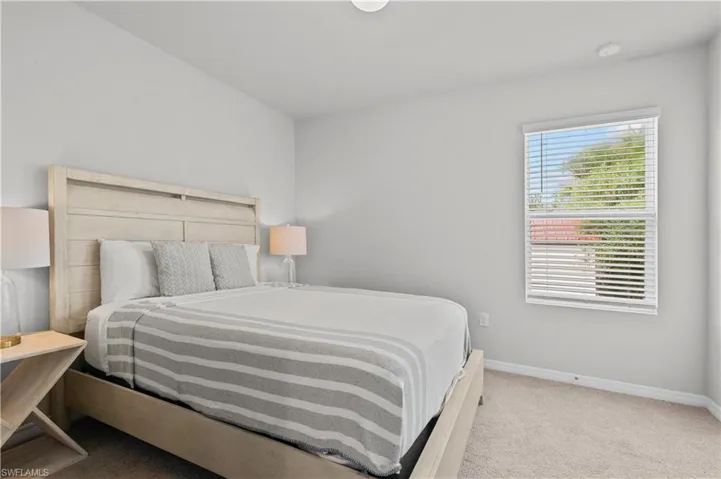 Bedroom featuring light carpet and baseboards