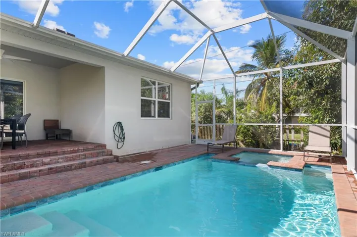 View of pool with a patio, glass enclosure, a pool with connected hot tub, and ceiling fan