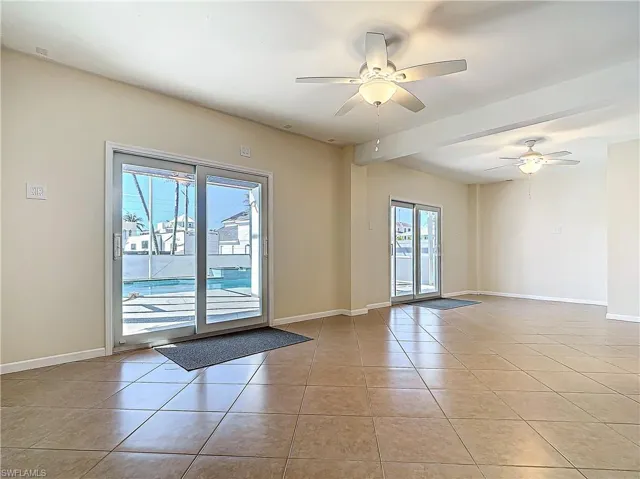 Spare room featuring light tile patterned floors, ceiling fan, and baseboards