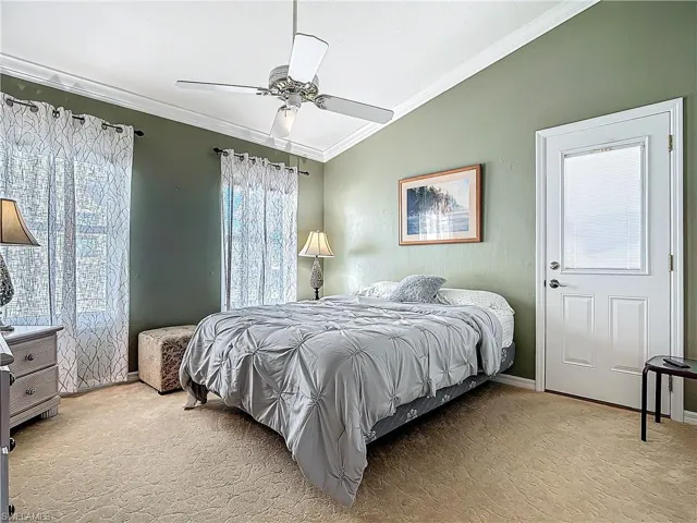 Bedroom with ceiling fan, lofted ceiling, light carpet, baseboards, and ornamental molding