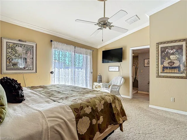 Bedroom with ornamental molding, lofted ceiling, visible vents, and light colored carpet
