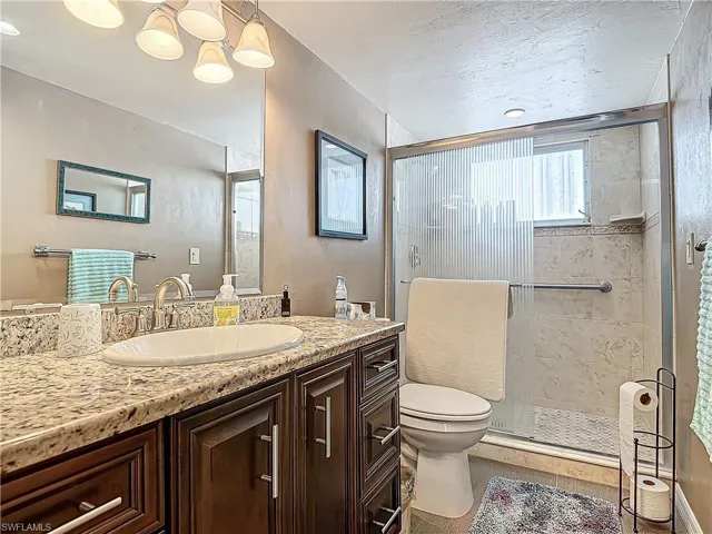 Bathroom featuring a textured ceiling, vanity, a shower stall, and toilet
