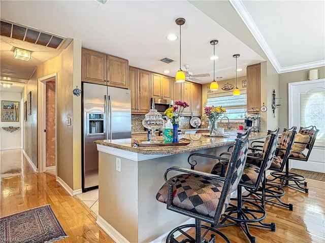 Kitchen featuring visible vents, a breakfast bar area, ornamental molding, stainless steel appliances, and stone counters