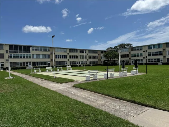 View of home's community with a bocce ball area, shuffleboard, and a lawn