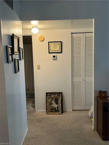 Corridor featuring carpet floors and baseboards