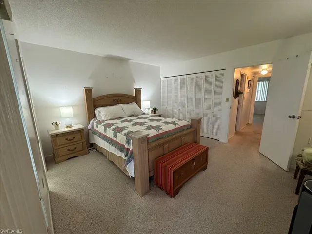 Bedroom featuring light colored carpet, a textured ceiling, and a closet