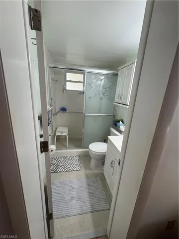 Ensuite bathroom featuring vanity, light tile patterned flooring, and a walk-in shower