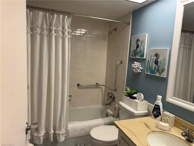 Bathroom featuring vanity and shower / bathtub combination with curtain